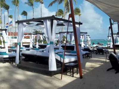 a group of chairs and umbrellas on a beach at Chic Beachfront Apartment - Private Beach Access in Punta Cana