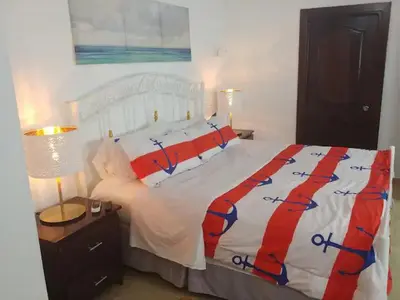 a bedroom with a white bed with a red and blue comforter at Dominican Suite 2, Increíble apto. cama king (DS2) in San Felipe de Puerto Plata