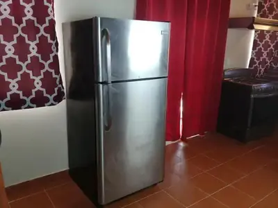 a stainless steel refrigerator in a kitchen with red curtains at Dominican Suite 2, Increíble apto. cama king (DS2) in San Felipe de Puerto Plata