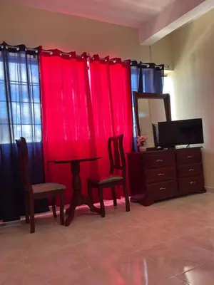 a living room with red curtains and a table and chairs at VBermor Hotel in Santo Domingo