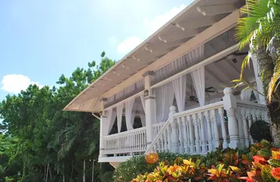 a white house with a white porch and flowers at Platino Hotel & Casino in Santiago de los Caballeros