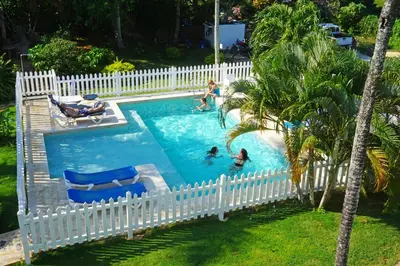a white fence around a swimming pool with people in it at B&B Aparthotel La Isleta in Las Galeras