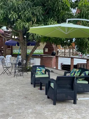 a group of patio chairs with a green umbrella at VILLA LOMAS LINDAS in La Montosa