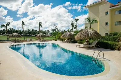 a swimming pool with chairs and umbrellas next to a building at Apartment Almas Iberosta Bavaro 3BDR with Pool & Private Beach in Punta Cana