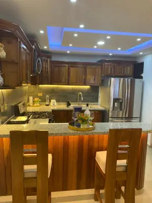 a kitchen with wooden cabinets and a kitchen island with chairs at VIP Home in Santiago de los Caballeros