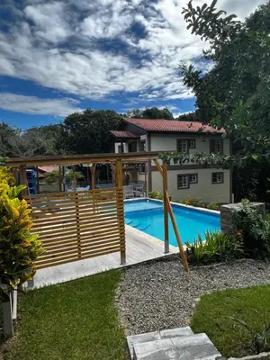 a wooden fence around a swimming pool in front of a house at Hacienda Claro de Luna 3 Bedrooms in Jarabacoa