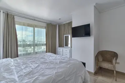 a white bedroom with a bed and a television at VIP Exclusive One Bedroom Apartment in Santo Domingo