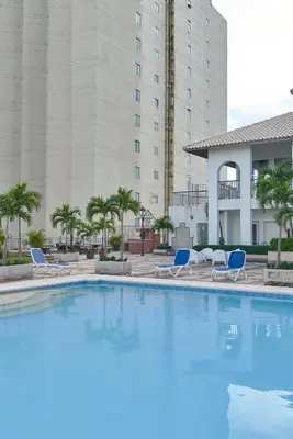 a large swimming pool with chairs and a building at VIP Exclusive One Bedroom Apartment in Santo Domingo