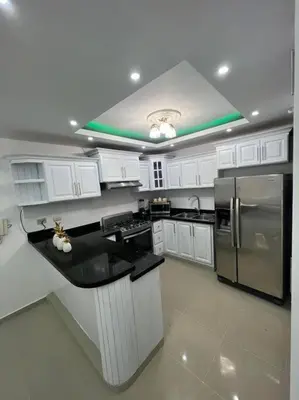 a kitchen with white cabinets and a stainless steel refrigerator at Luxury apartment with Pool in Santiago de los Caballeros