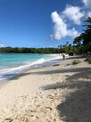 a beach with people walking on the sand and the ocean at Bungalow de Ballenas in Punta Balandra