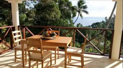 a table and chairs on a balcony with a view of the ocean at Bungalow de Ballenas in Punta Balandra