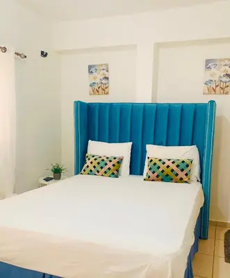 a large bed with a blue headboard in a room at Villa Marcia in Boca Chica
