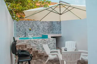 a patio with white chairs and an umbrella at D' Yoko Village's in Pedernales