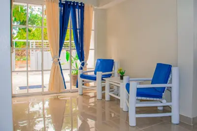 two blue chairs and a table in a room with a window at D' Yoko Village's in Pedernales