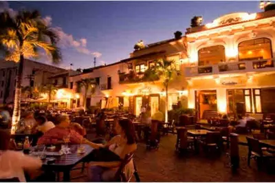 a group of people sitting at a restaurant at night at Cerca del Mar, Obelisco Macho y Zona Colonial in Santo Domingo