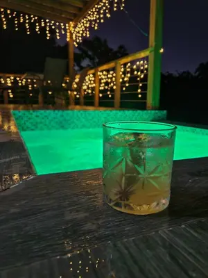 a glass of drink sitting on a table next to a pool at Villa en la montaña in Jarabacoa