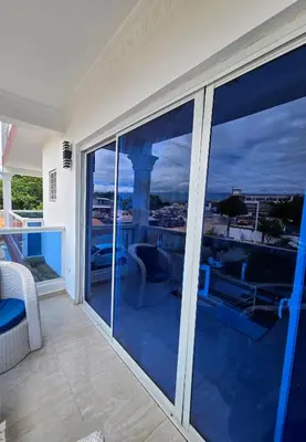 a balcony with glass doors with a view of the ocean at Madome Aparta Hotel in Pedernales