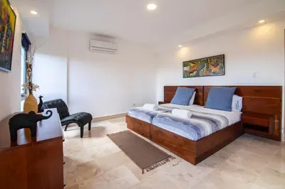 a bedroom with a large wooden bed with blue pillows at Beachfront penthouse - Amar'e Aparthotel & Spa in Las Terrenas