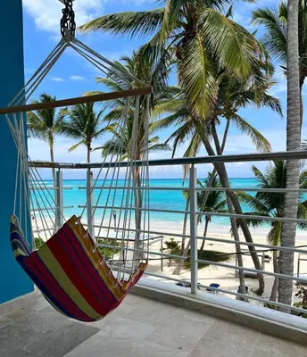 a hammock hanging from a balcony overlooking the beach at Private room overlooking the beach in Punta Cana