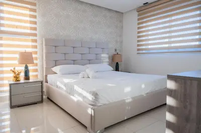 a white bedroom with a large bed and a window at Top Floor in Luxury Tower in Santiago de los Caballeros