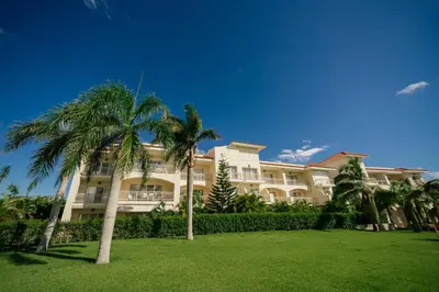 a large building with palm trees in front of it at Spacious Iberosta ApartmentSueno - 3BDR Pool, Beach, WiFi in Punta Cana