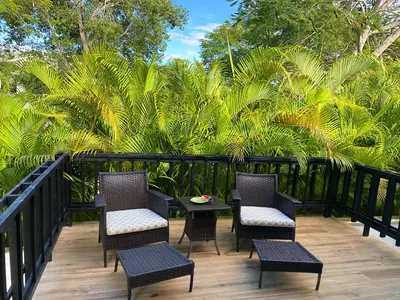 a patio with chairs and a table and palm trees at Beach Apartment Villas Jubey, Emotion access in Juan Dolio