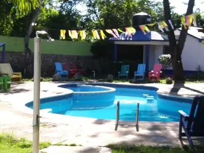 a swimming pool in a yard with colorful chairs at Hacienda de Flores in Guayacanes
