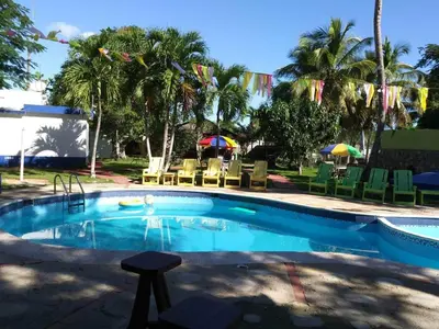 a swimming pool with chairs and umbrellas in a yard at Hacienda de Flores in Guayacanes