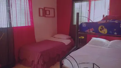 two beds in a room with red walls and windows at Hacienda de Flores in Guayacanes