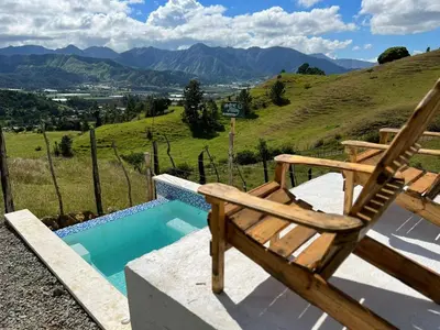 a wooden chair sitting next to a swimming pool at La Casita de Charo 1, disfruta de tiempo memorable en la montaña in Constanza
