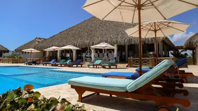a pool with chairs and umbrellas next to a resort at Unique 1BDR Retreat with pool at Hard Rock Golf C. in Punta Cana
