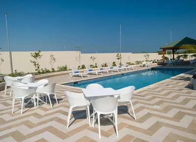 a pool with white tables and chairs next to a pool at Super 8 by Wyndham Manzanillo in Pepillo Salcedo