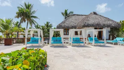 a resort with blue chairs and a thatch roof at Golf & Lake View Oasis •Private Jacuzzi •Hard Rock in Punta Cana