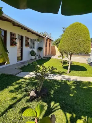 a yard with a house and a tree in the yard at Habitación Hogareña in Jarabacoa