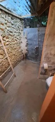 a bathroom with a shower and a stone wall at Casita de Madera Encuentro in Bombita