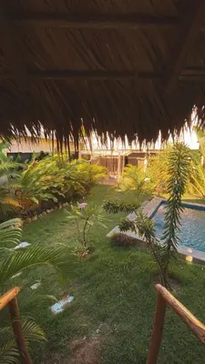 a resort yard with a swimming pool and a large umbrella at Casita de Madera Encuentro in Bombita