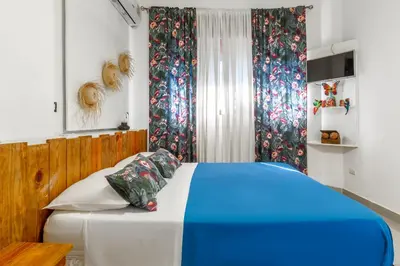 a blue and white bed in a room with curtains at Hostal Mamà Mambò - Zona Colonial in Santo Domingo