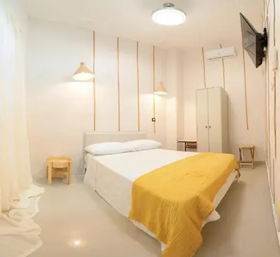 a bedroom with a bed with a yellow blanket on it at Hostal Mamà Mambò - Zona Colonial in Santo Domingo