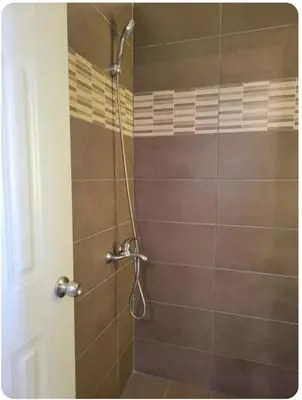 a bathroom with a shower with brown tile at Amplio apartmento in Santo Domingo