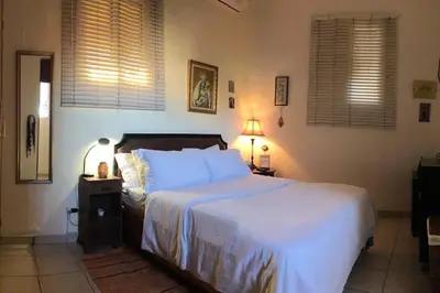 a bedroom with a bed with white sheets and a lamp at Centerpice Colonial Zone in Santo Domingo