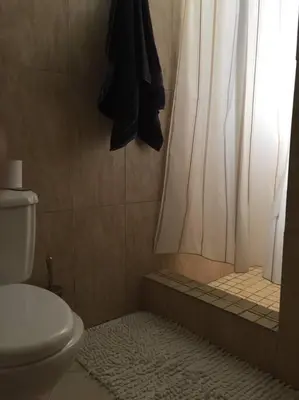 a bathroom with a toilet and a shower with a curtain at Centerpice Colonial Zone in Santo Domingo