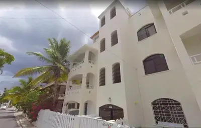 a white building with a palm tree in front of it at Venere Bayahibe by Mireya in Bayahibe