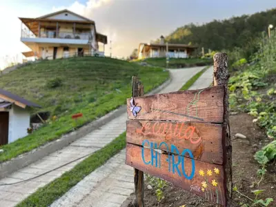 a sign on the side of a dirt road at La Casita de Charo 2, vive y siente el amor, creando recuerdos de vida!! in Constanza