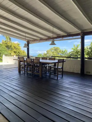 a wooden deck with a table and chairs on it at Propiedad de alto standing con vista al mar, piscina, tenis, hasta 12 personas in Las Terrenas