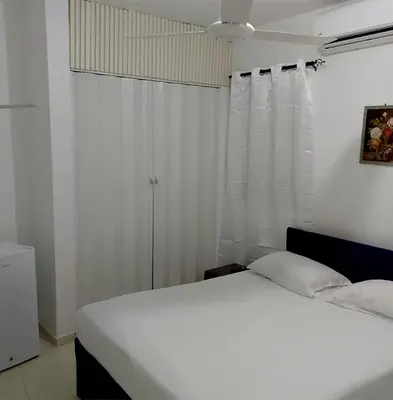 a bedroom with a white bed and a white curtain at Hotel Ningo in Santa Bárbara de Samaná