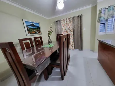 a dining room with a wooden table and chairs at Hermoso y comodo apartamento in Santiago de los Caballeros
