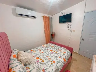 a small bedroom with a bed and a room with a fan at Acogedora casa de 2 habitaciones in Villa Isabela