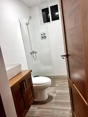 a bathroom with a toilet and a glass shower at Outstanding Pent House w/Jacuzzi in Santiago de los Caballeros