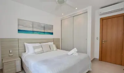 a bedroom with a white bed and a wooden door at Beach Garden I F3 Luxury Condo in Punta Cana