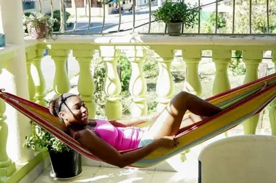 a woman laying in a hammock on a balcony at Apartamento en la Romana 2 días en adelante in La Romana